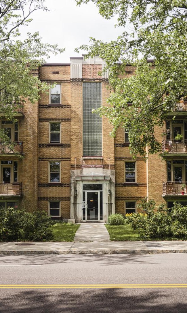 Three-story brick apartment building with an entrance walkway